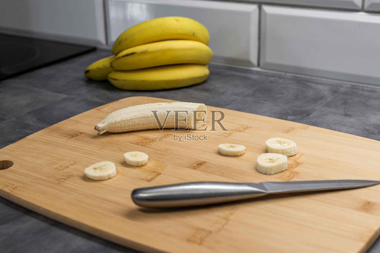 切好的香蕉放在木砧板上，旁边有一把刀照片摄影图片