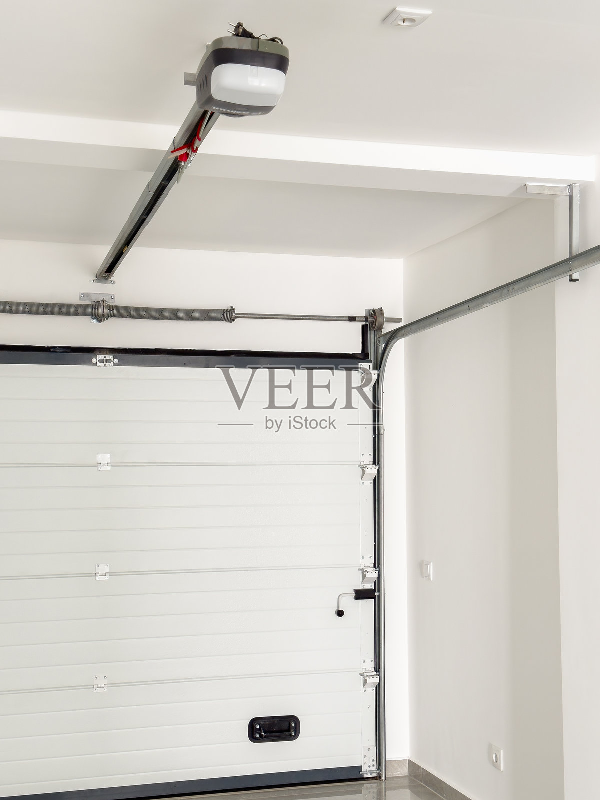 白色自动车库门，配有电动开门器和金属支撑系统。照片摄影图片