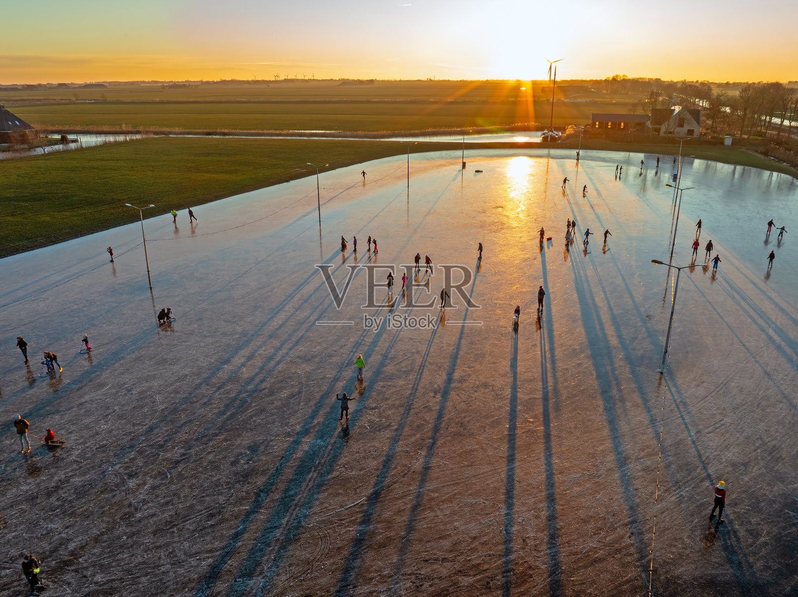荷兰弗里斯兰省库杜姆的冰场上日落时分的冰上滑冰航拍图照片摄影图片