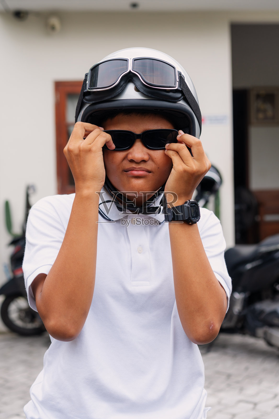 自信的年轻骑手调整着太阳镜和摩托车头盔照片摄影图片