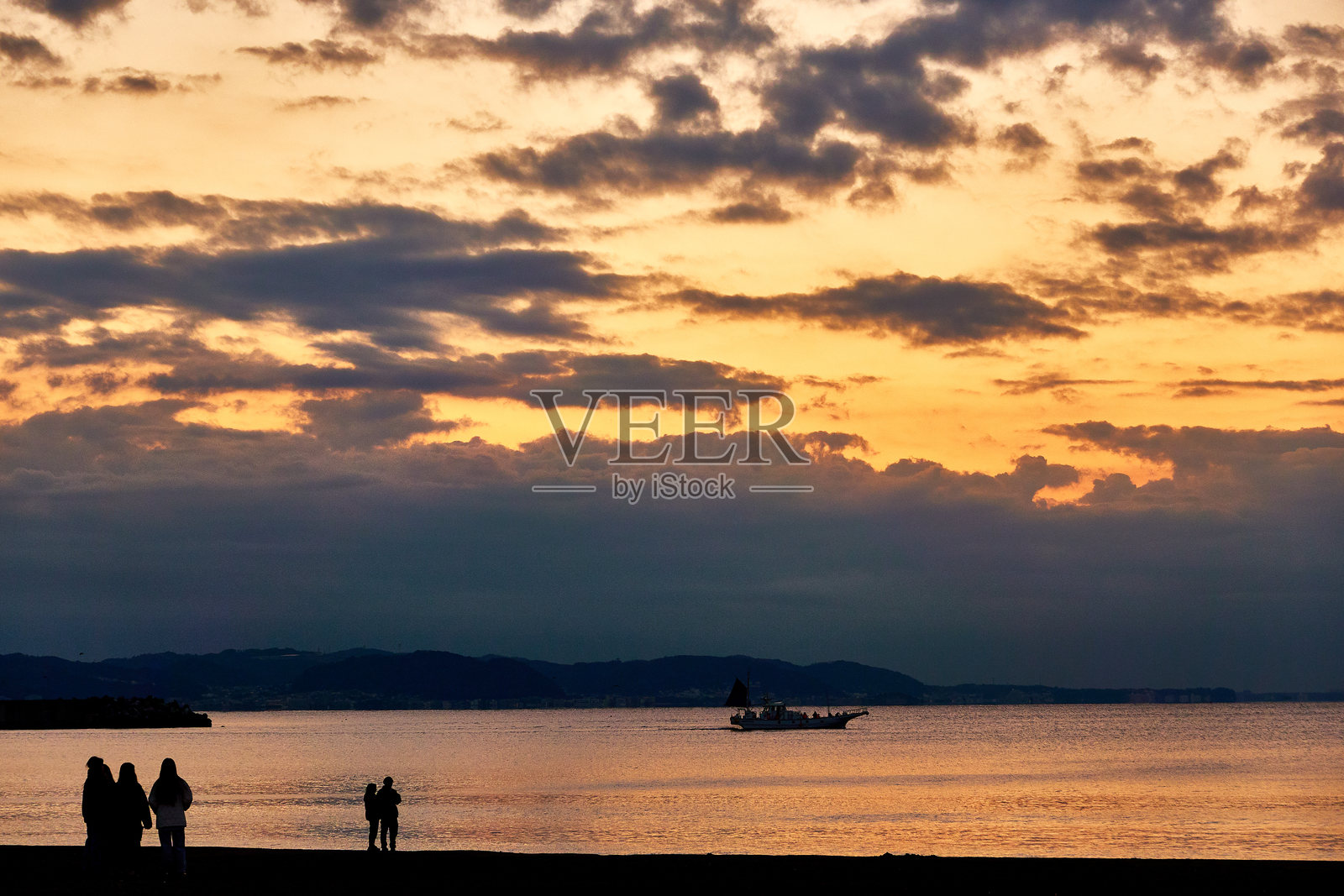 日出时分，海滩上人们的剪影与戏剧性的天空相映成趣照片摄影图片
