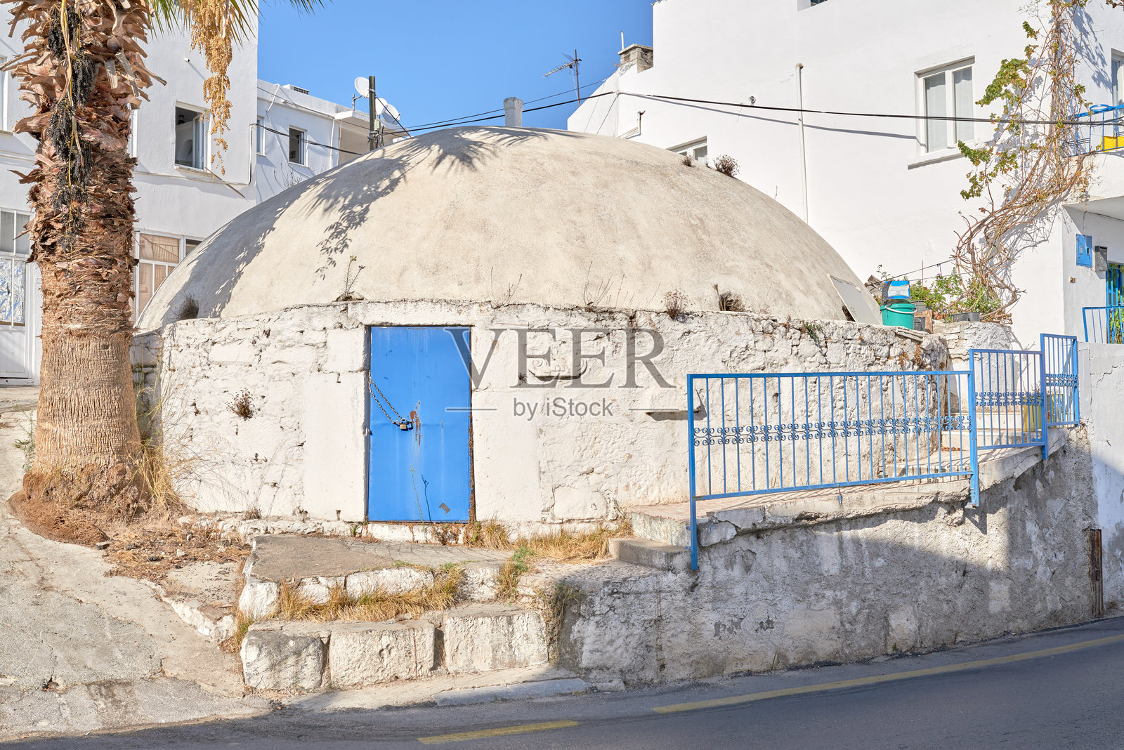 阳光明媚的土耳其街道上，一座带蓝色门的历史圆顶建筑照片摄影图片