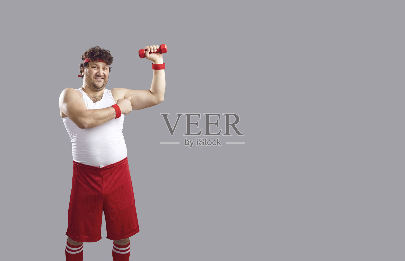 微笑的胖男孩手持哑铃并弯曲手臂，背景为空白空间照片摄影图片