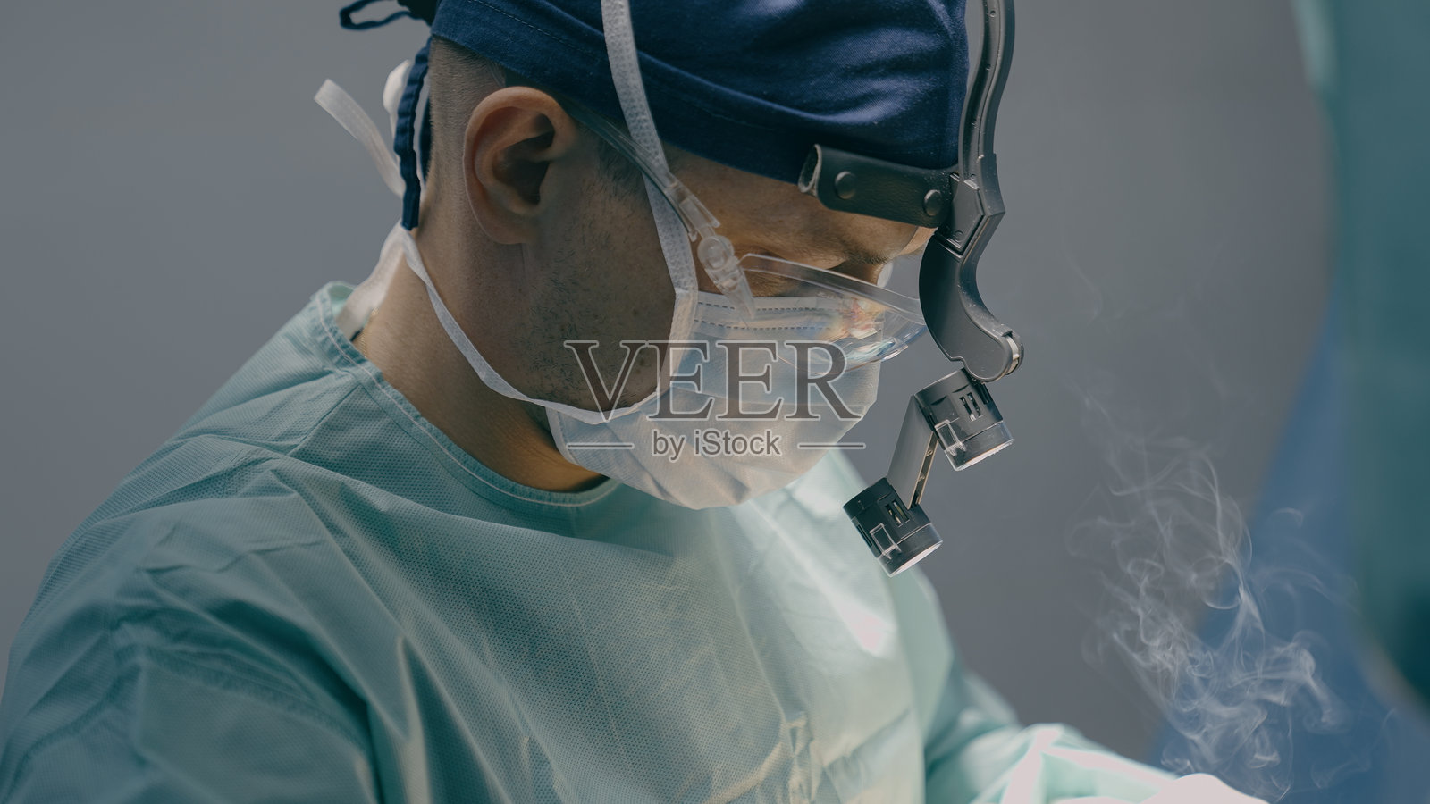 特写医生，男，医师，外科医生，佩戴保护性医用口罩，进行显微镜下的整形手术，使用电凝器，现代医疗治疗，医院，医疗保健。照片摄影图片