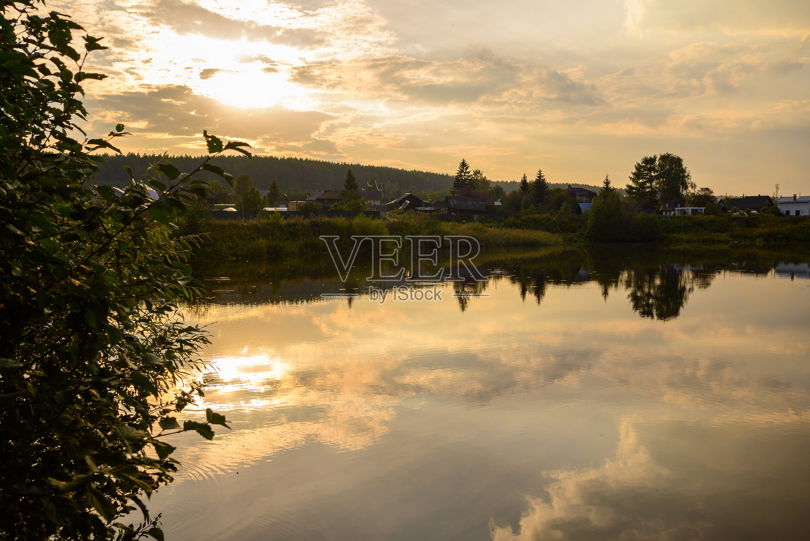 美丽的橙色日落在大自然中，森林和湖面上云彩的倒影。照片摄影图片