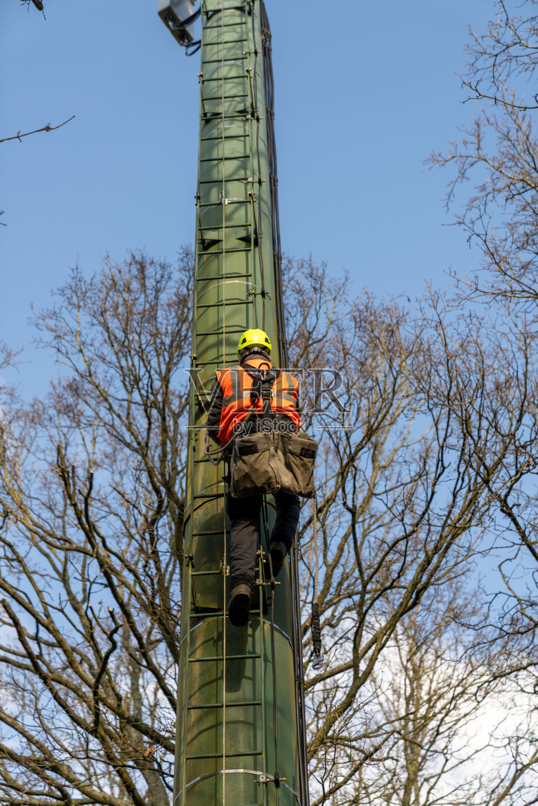 穿着安全背心的男子正在攀爬一根电杆照片摄影图片