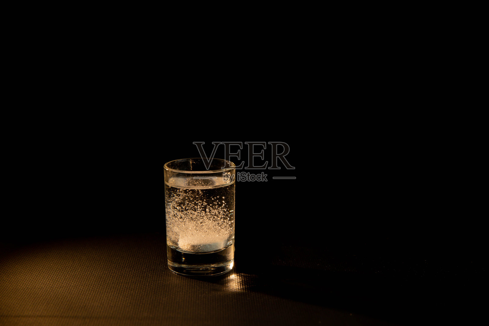 黑色背景下的水杯与泡腾溶解片照片摄影图片