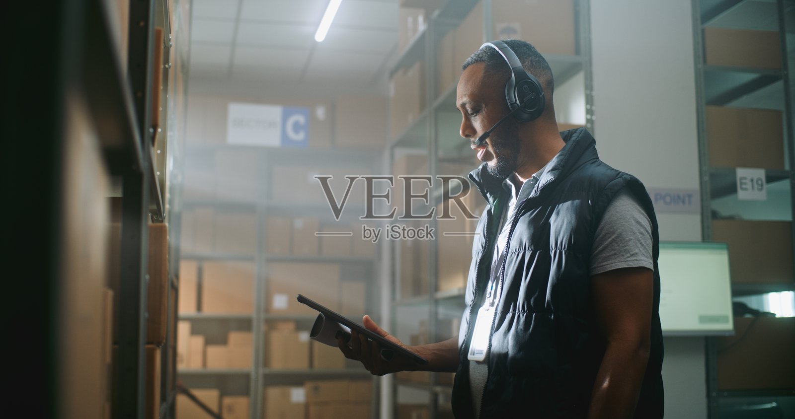 非裔美国人仓库员工与客户交谈，使用平板电脑，面向镜头。照片摄影图片