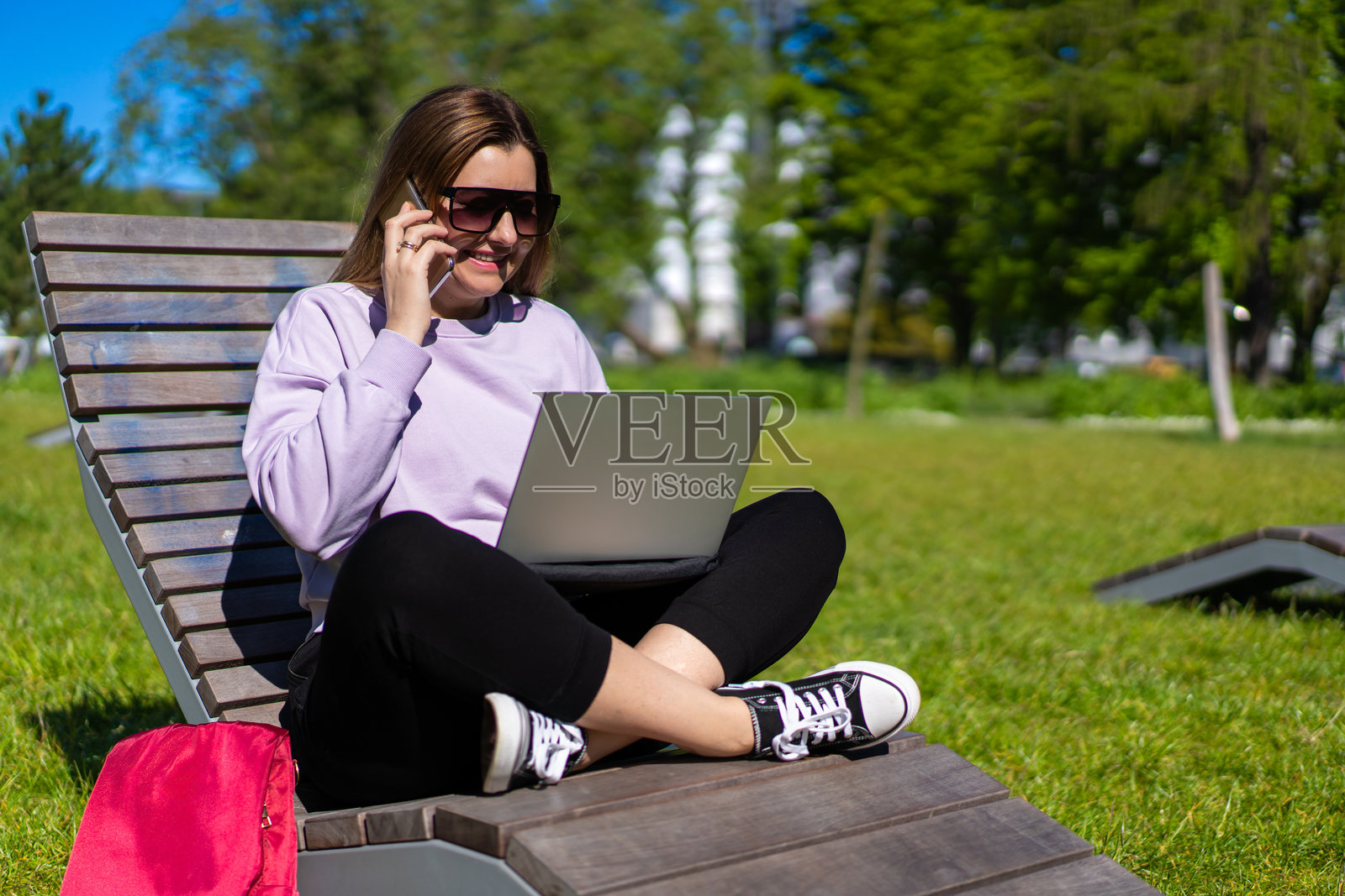 美丽的成熟的女性在城市公园的长椅上使用智能手机和笔记本电脑照片摄影图片