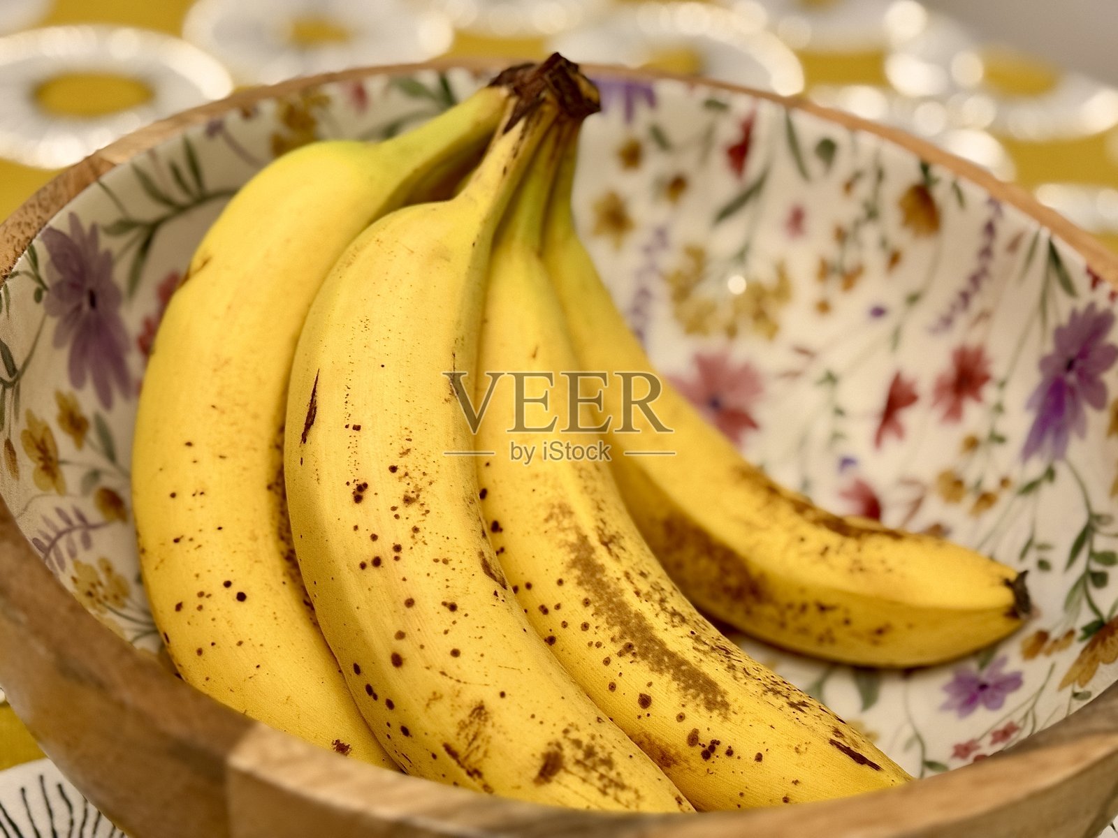 一个盛满成熟香蕉的花卉风格碗，随时可以享用照片摄影图片