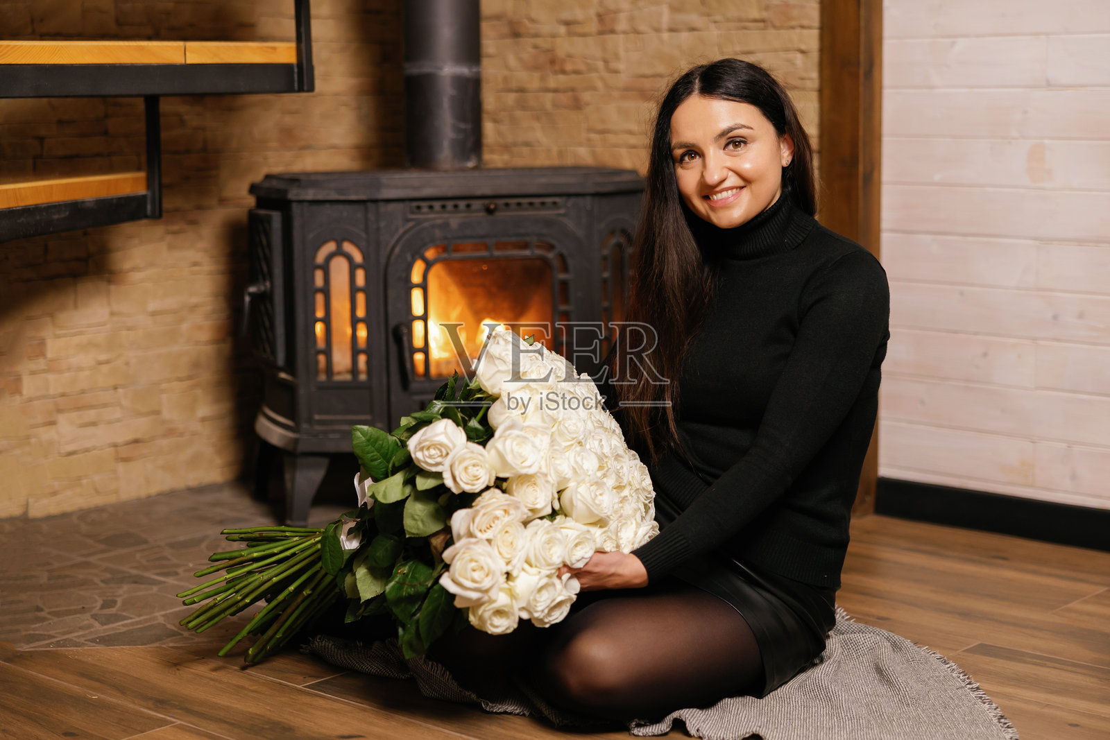 女人在壁炉旁捧着一大束白玫瑰照片摄影图片