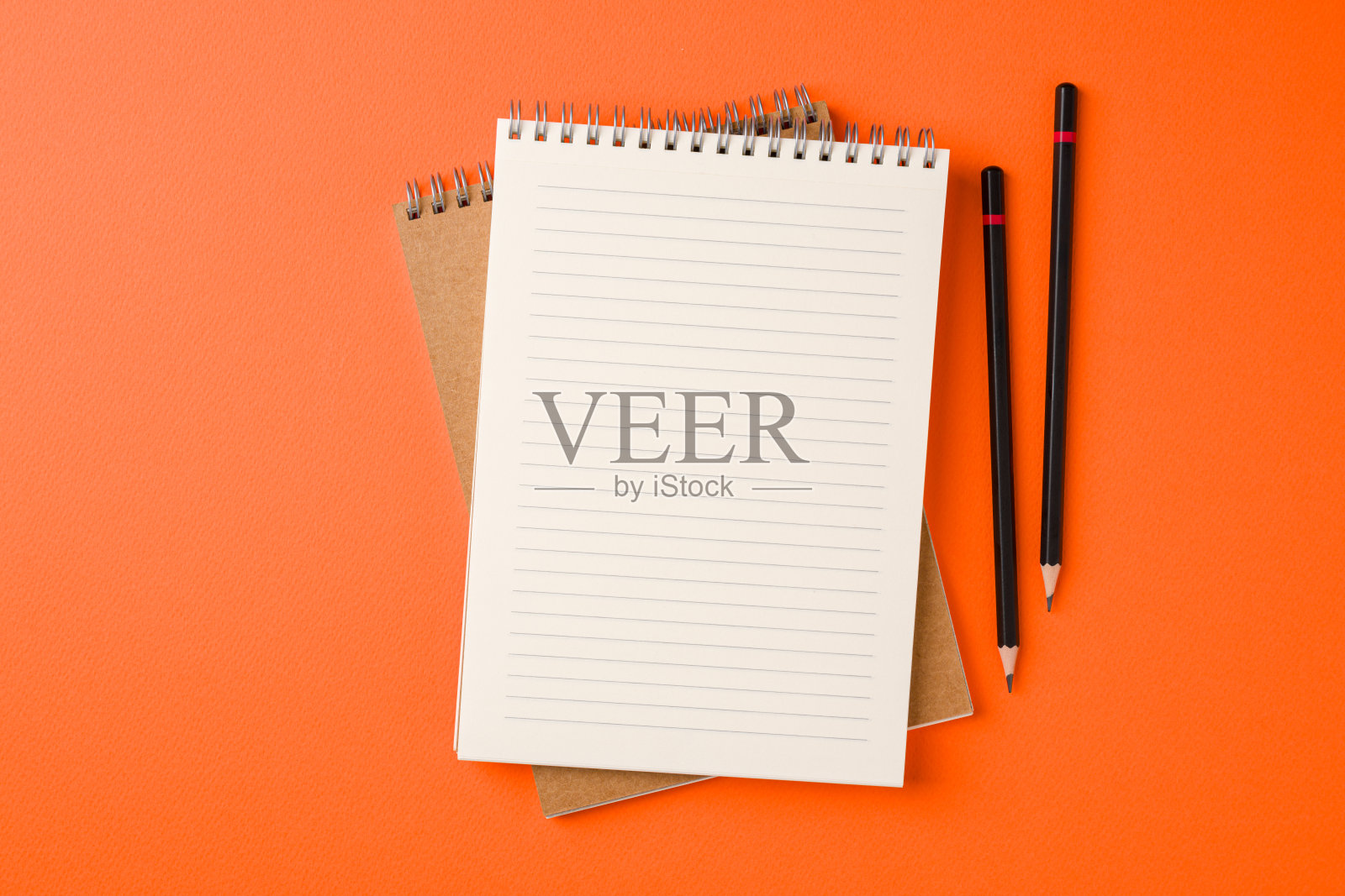 橙色背景上的笔记本和圆珠笔的俯视图照片摄影图片