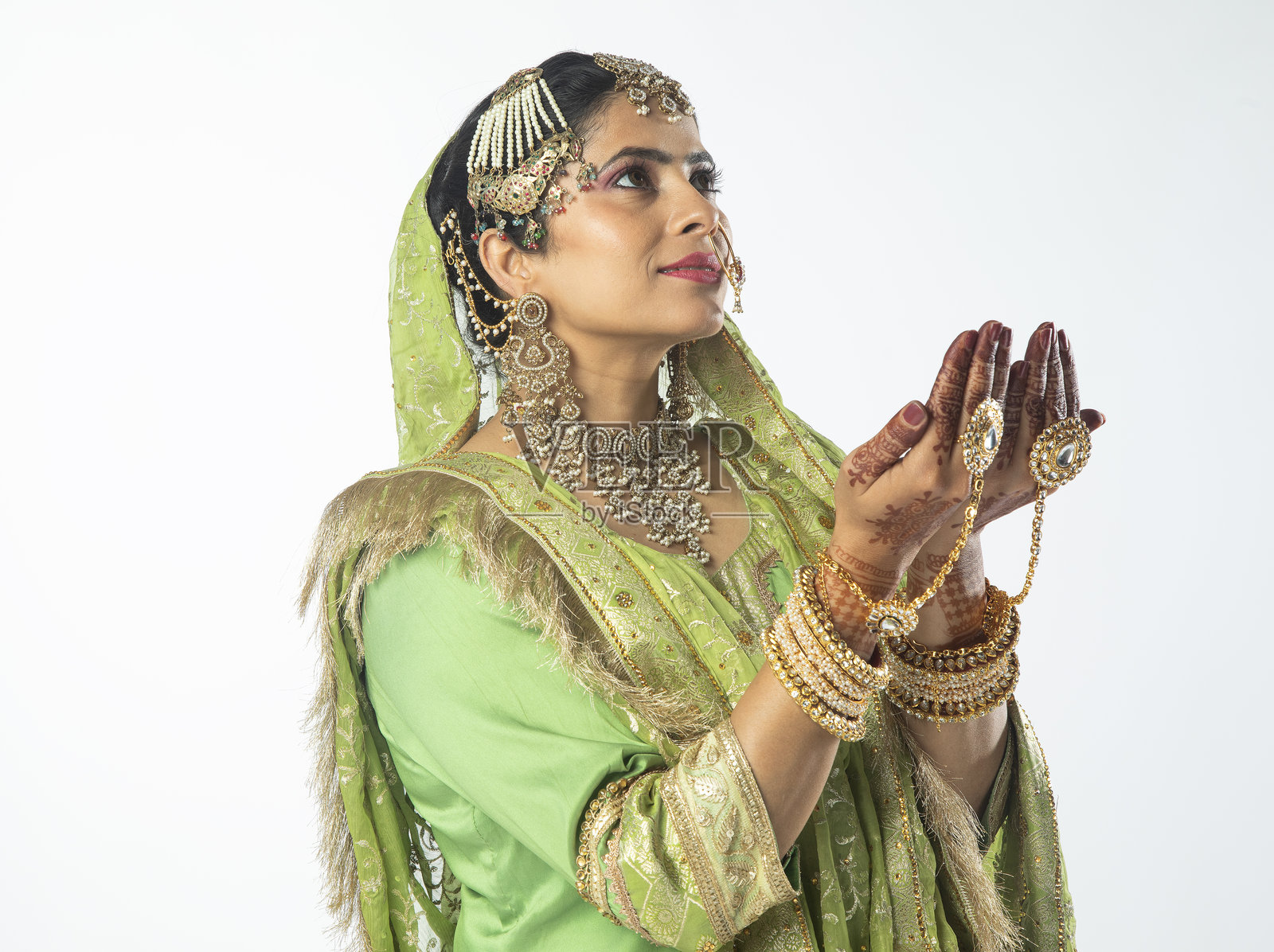 身穿绿色礼服和珠宝的新人在白色背景下祈祷的肖像照片摄影图片