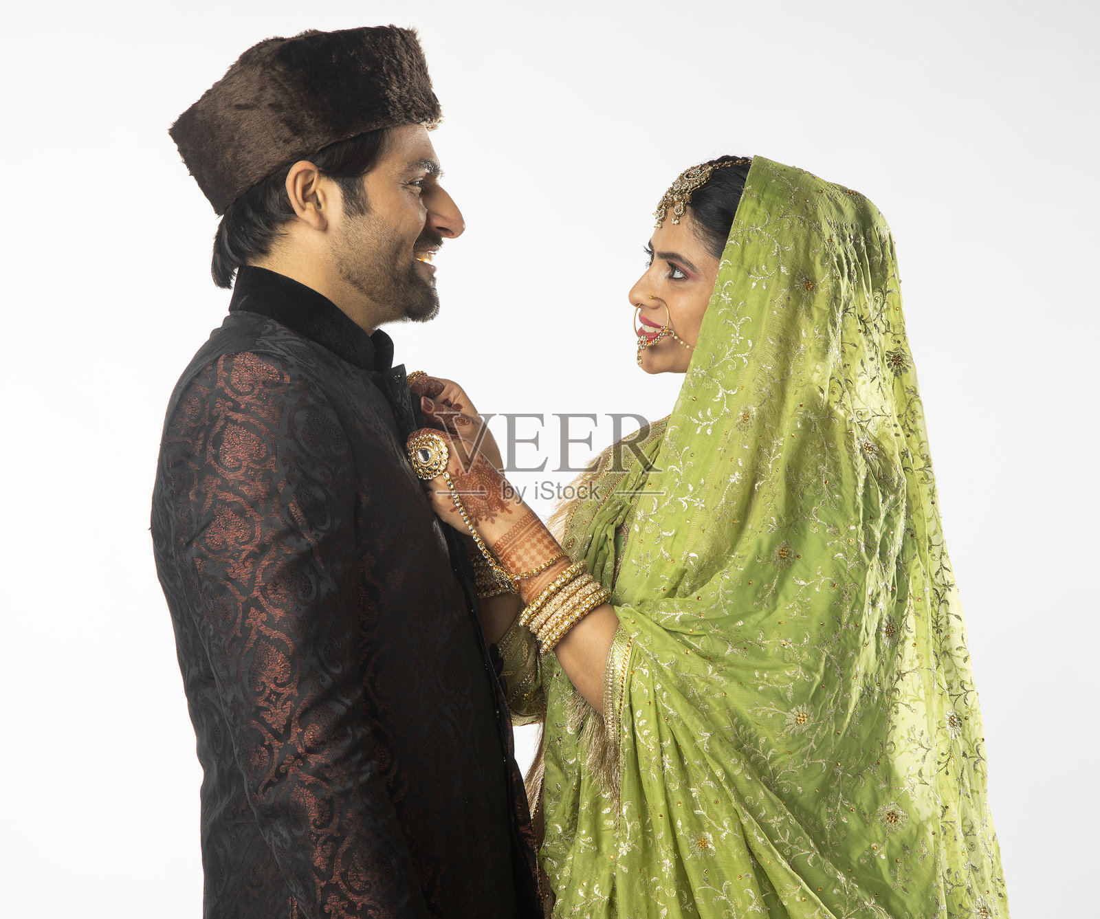 新娘在白色背景下为新郎扣上库尔塔。照片摄影图片