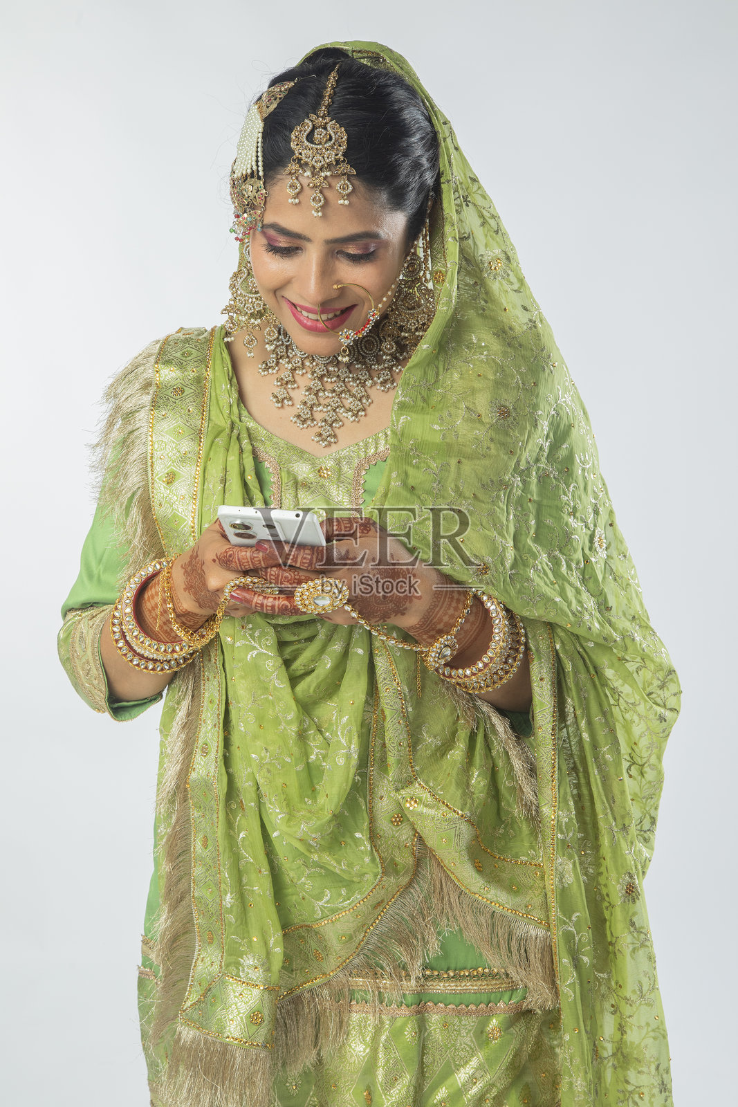 穿着婚纱的新娘在白色背景上用智能手机发短信照片摄影图片