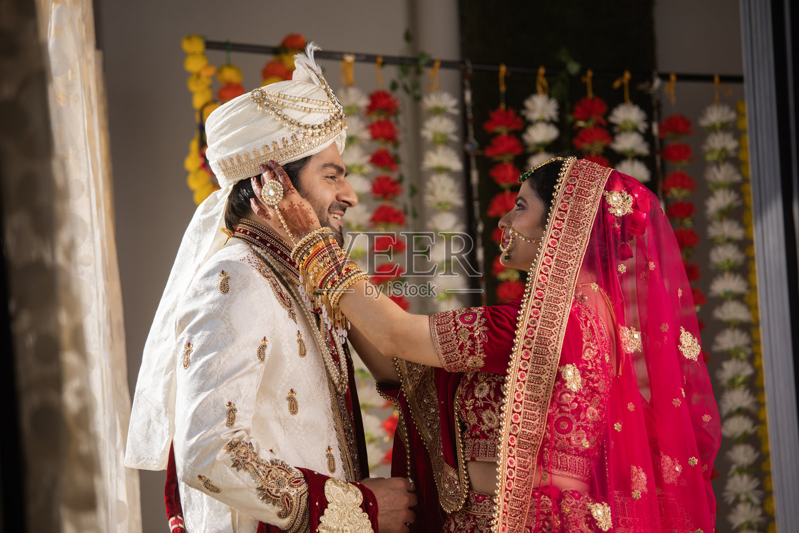 新娘身着传统服饰，轻触新郎的脸庞照片摄影图片