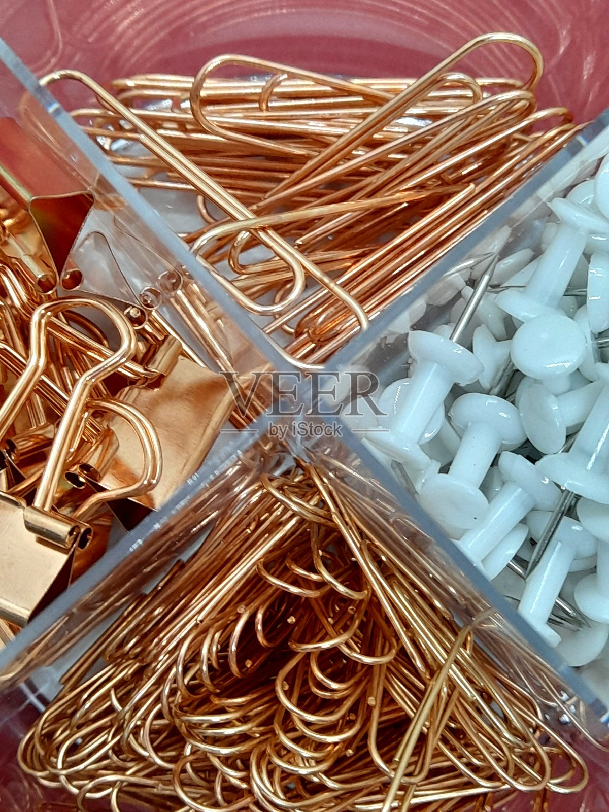 金色回形针在塑料盒中。照片摄影图片