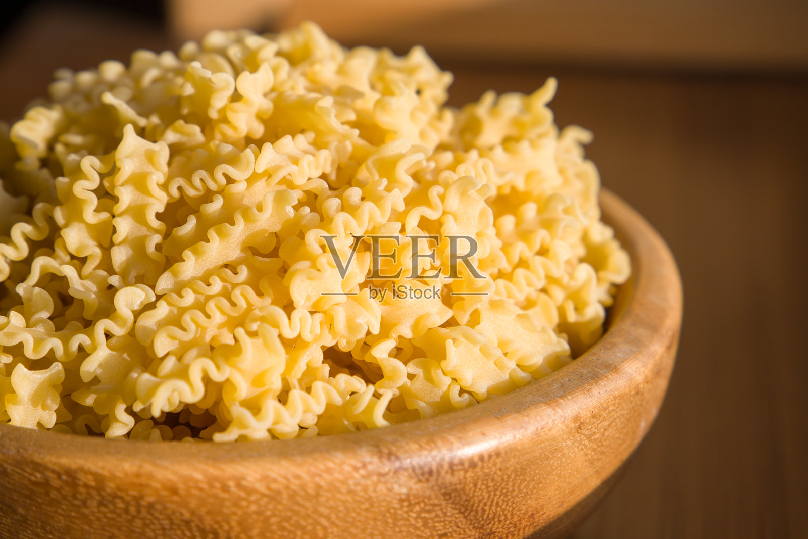 木桌上的木碗里装着生意大利面马法尔达的生通心粉。特写镜头，选择性对焦。照片摄影图片