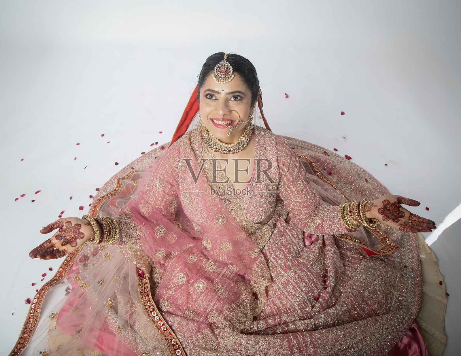 花瓣飘落在兴奋的新娘身上，背景为白色。照片摄影图片