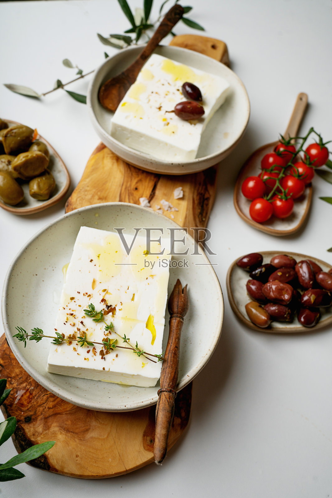 传统希腊羊奶酪与橄榄树板上的橄榄枝照片摄影图片