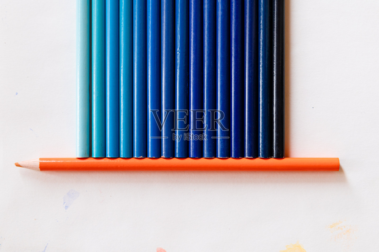 蓝色铅笔的不同色调放在一支橙色铅笔上照片摄影图片