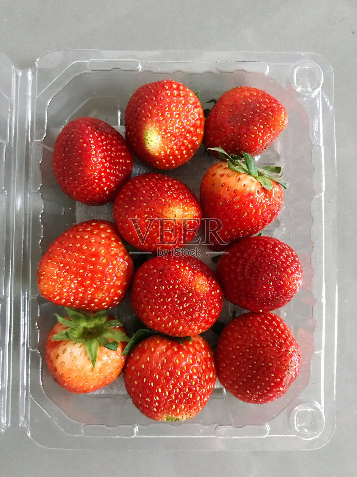 白色背景上的塑料盒中的草莓，俯视图。照片摄影图片