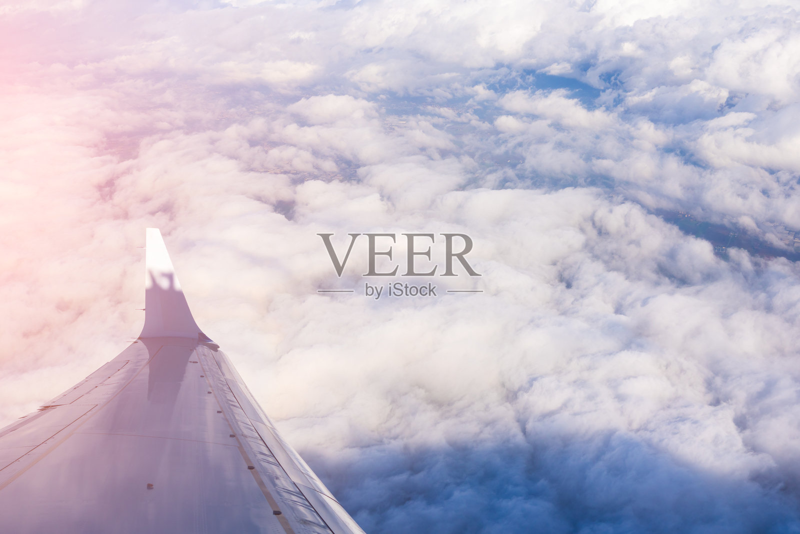 白天飞行时从飞机机翼上俯瞰高空的云朵与大地景观照片摄影图片