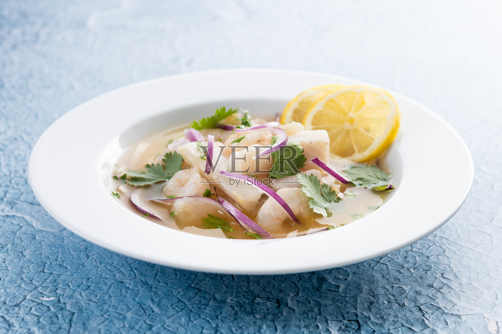 传统秘鲁酸橘汁腌鱼海鲈鱼片，背景为蓝色照片摄影图片