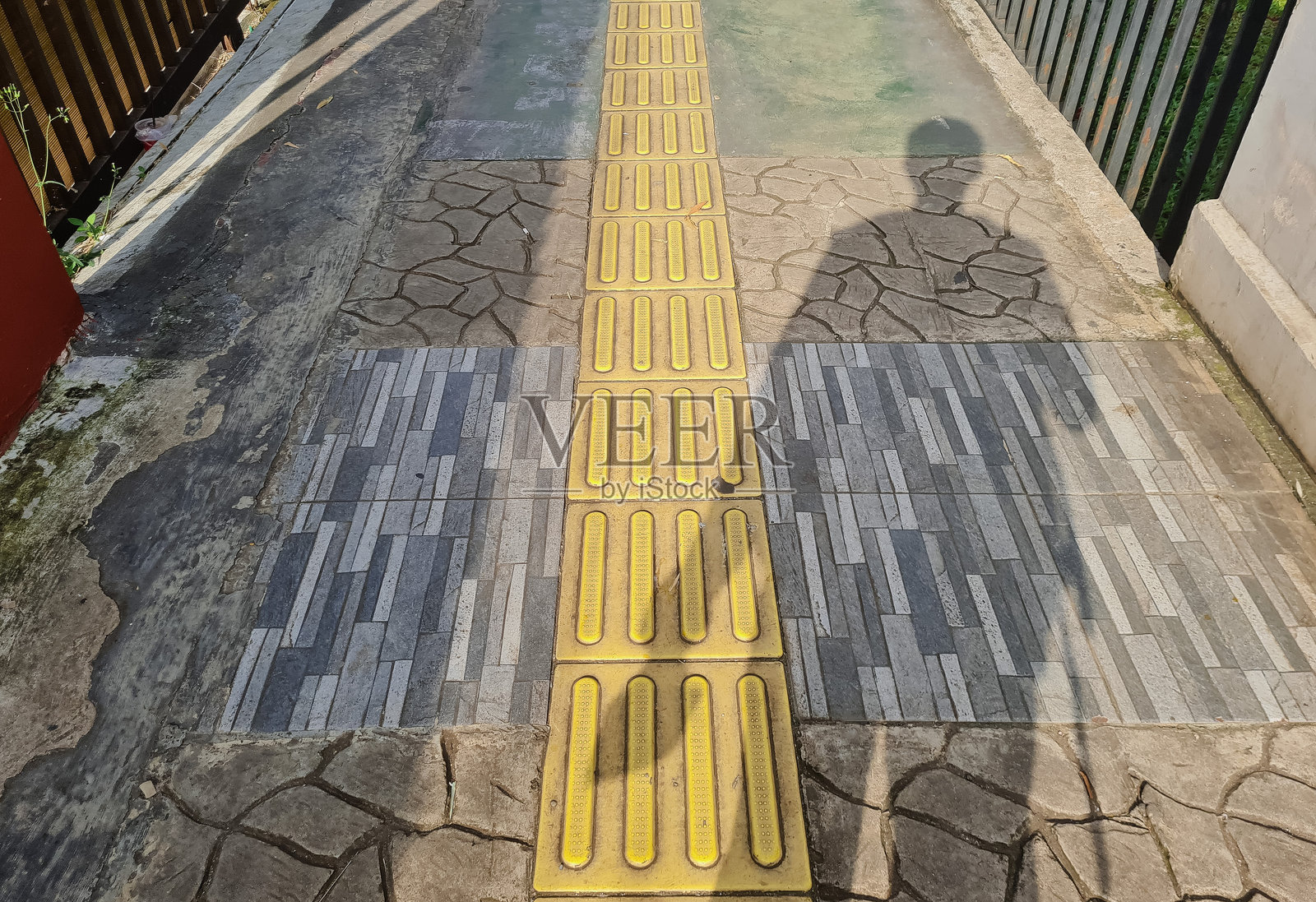 巷子里的黄色触觉砖是盲人的行走指引。照片摄影图片