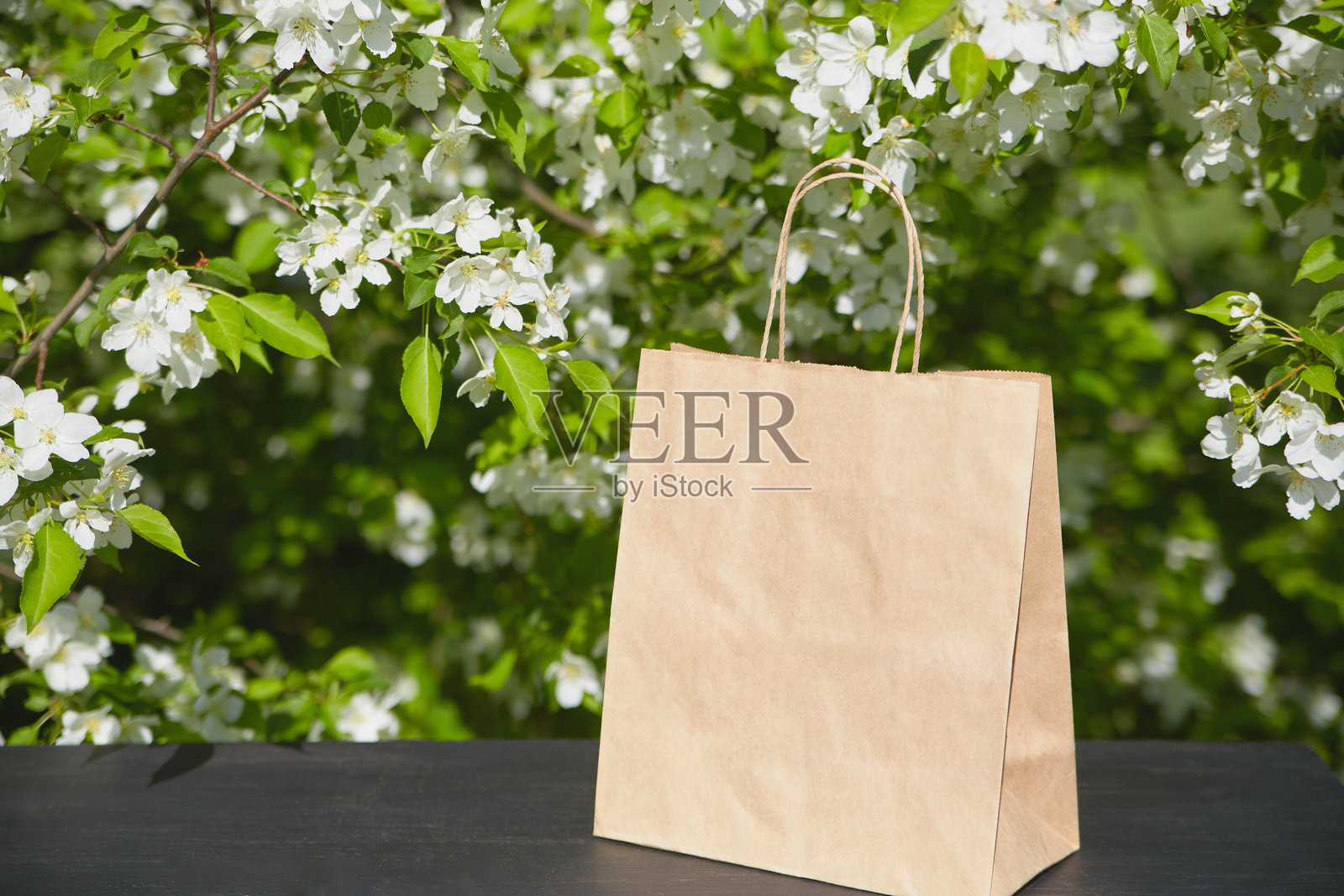 春天盛开的花朵旁边放着一个棕色纸袋的桌子照片摄影图片