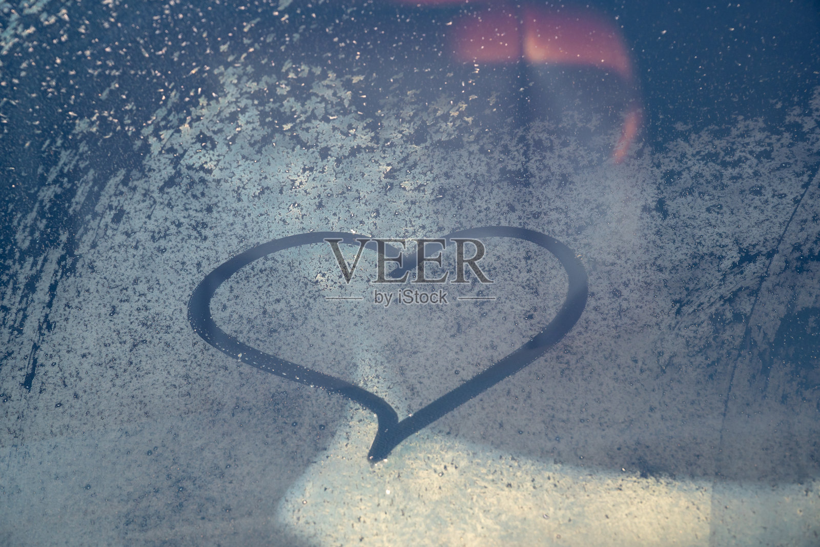 情人节概念：冰冻汽车挡风玻璃上的手绘心形图案。汽车挡风玻璃上的手绘心形。爱的象征。照片摄影图片