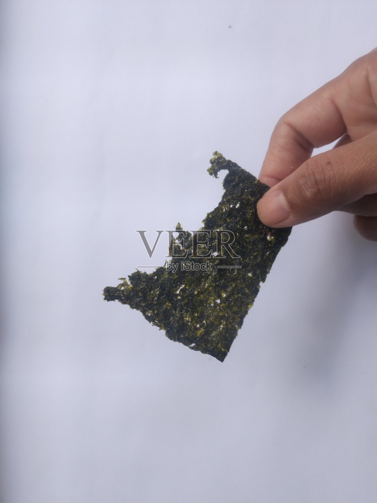 手持脆海苔，白色背景留有空白。干燥的紫菜片，韩国或日本烤制食品的质感。俯视图。照片摄影图片