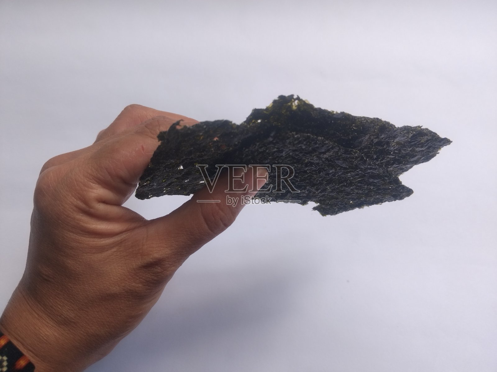 白色背景上手握脆海苔，留有空白空间。干燥的紫菜片，韩国或日本烤制食品的质感。平铺展示。照片摄影图片