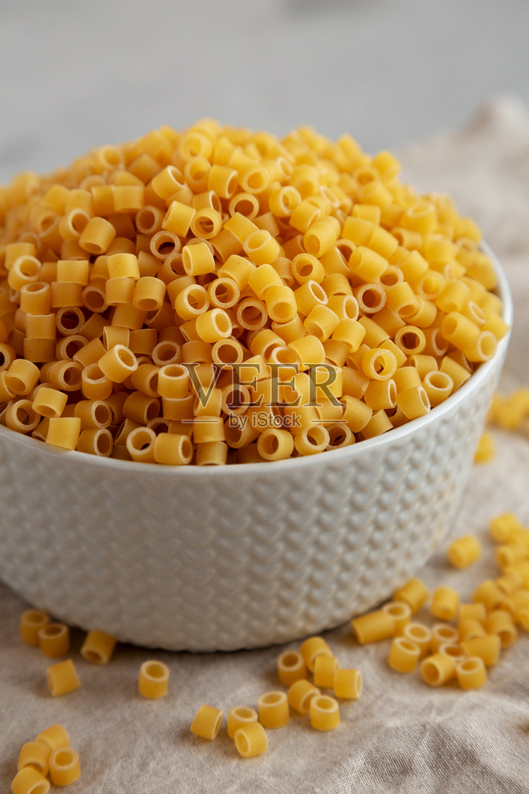 灰色背景下碗中的生意大利小管面，低角度视图，特写。照片摄影图片