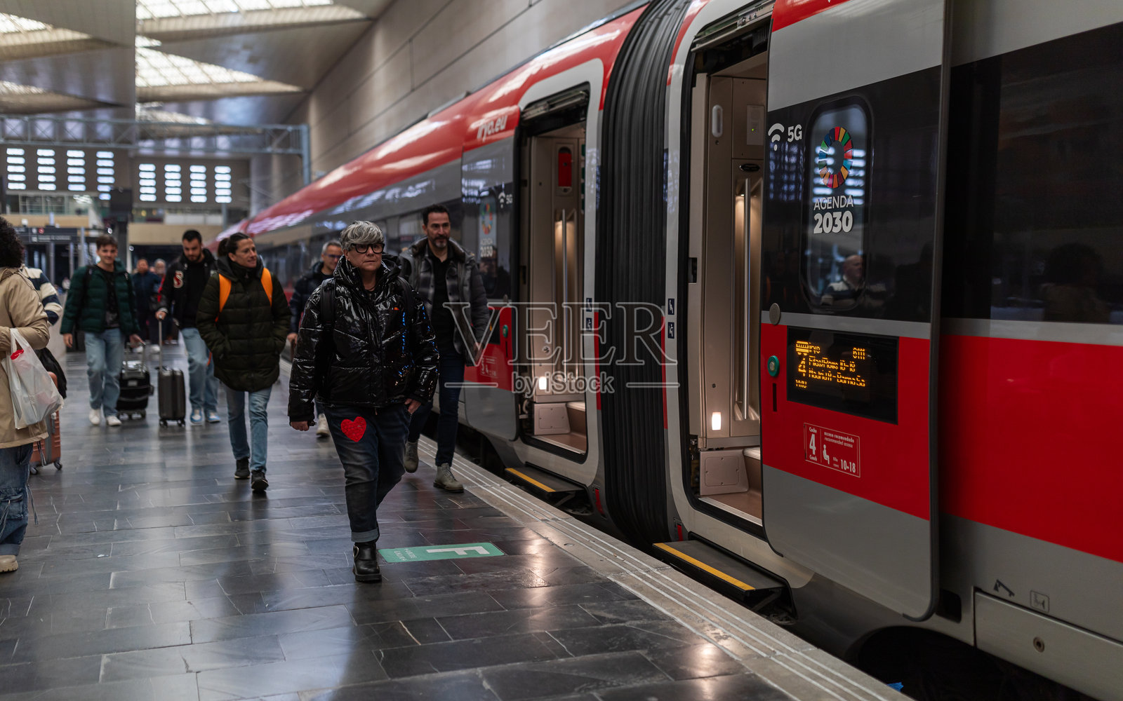 西班牙萨拉戈萨 - 2024年3月6日：乘客在萨拉戈萨德利西亚斯火车站的站台上走动，旁边停着一列Iryo公司的高速列车。照片摄影图片