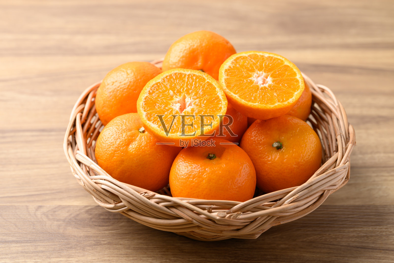 木质背景上的篮子里装着的橘子水果照片摄影图片