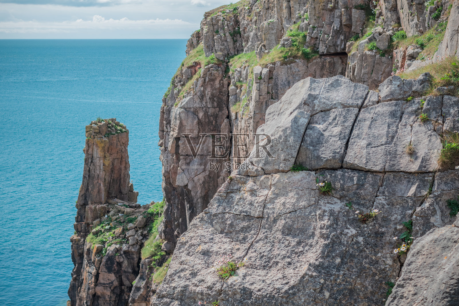 在英国威尔士西南部的圣戈文角，一座高耸的海岸岩石形成物矗立在深蓝色的海洋上。照片摄影图片