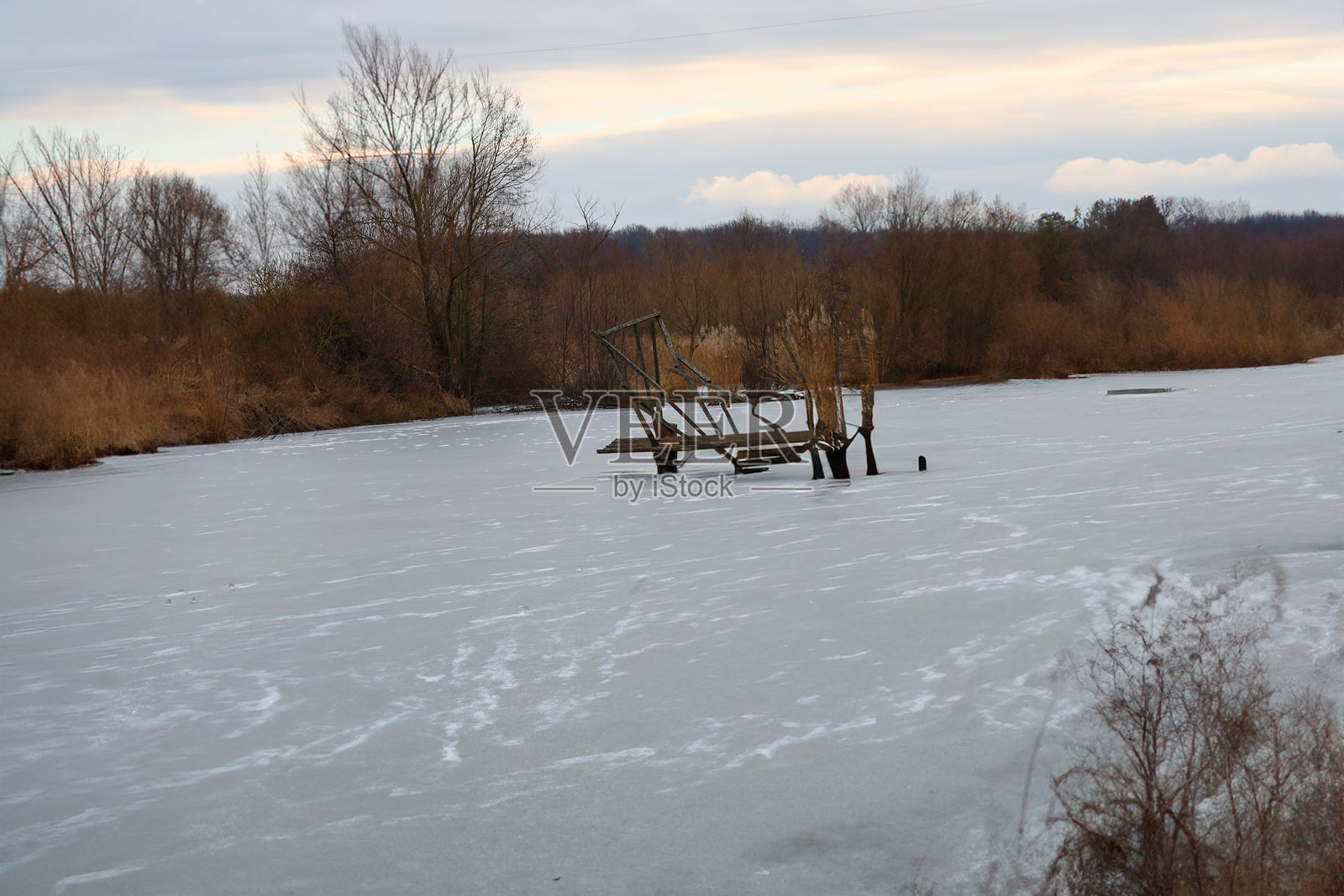 一个木平台建在池塘中央，池塘已经结冰。冬季池塘的美丽风景。自然度假的主题。照片摄影图片