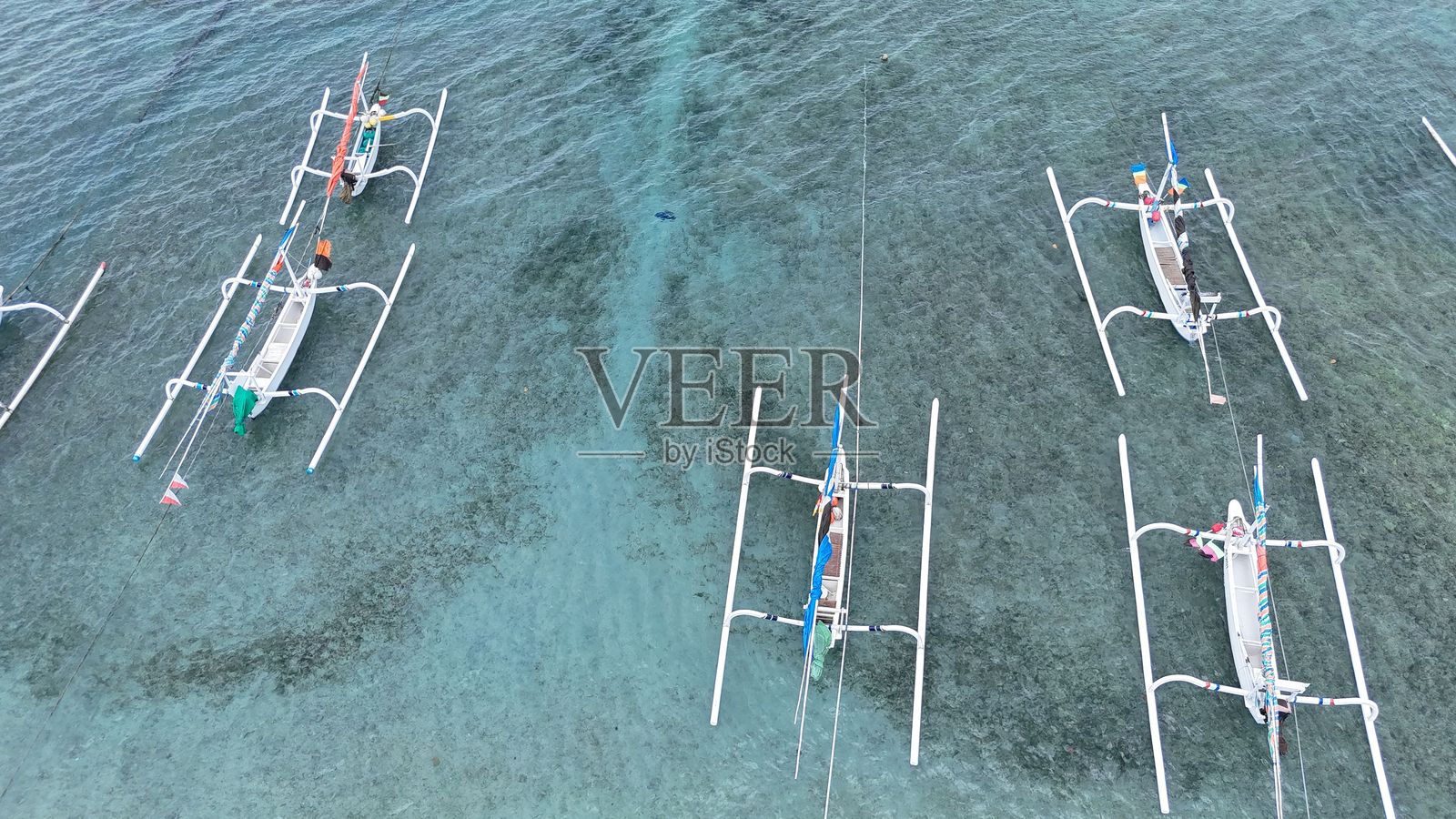 巴厘岛碧蓝海水中的传统渔船。照片摄影图片