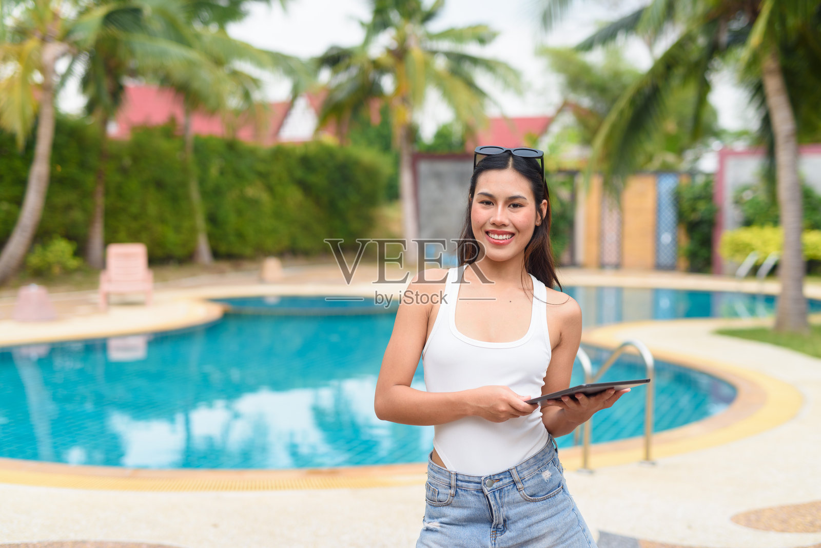 在游泳池旁使用平板电脑的女性照片摄影图片