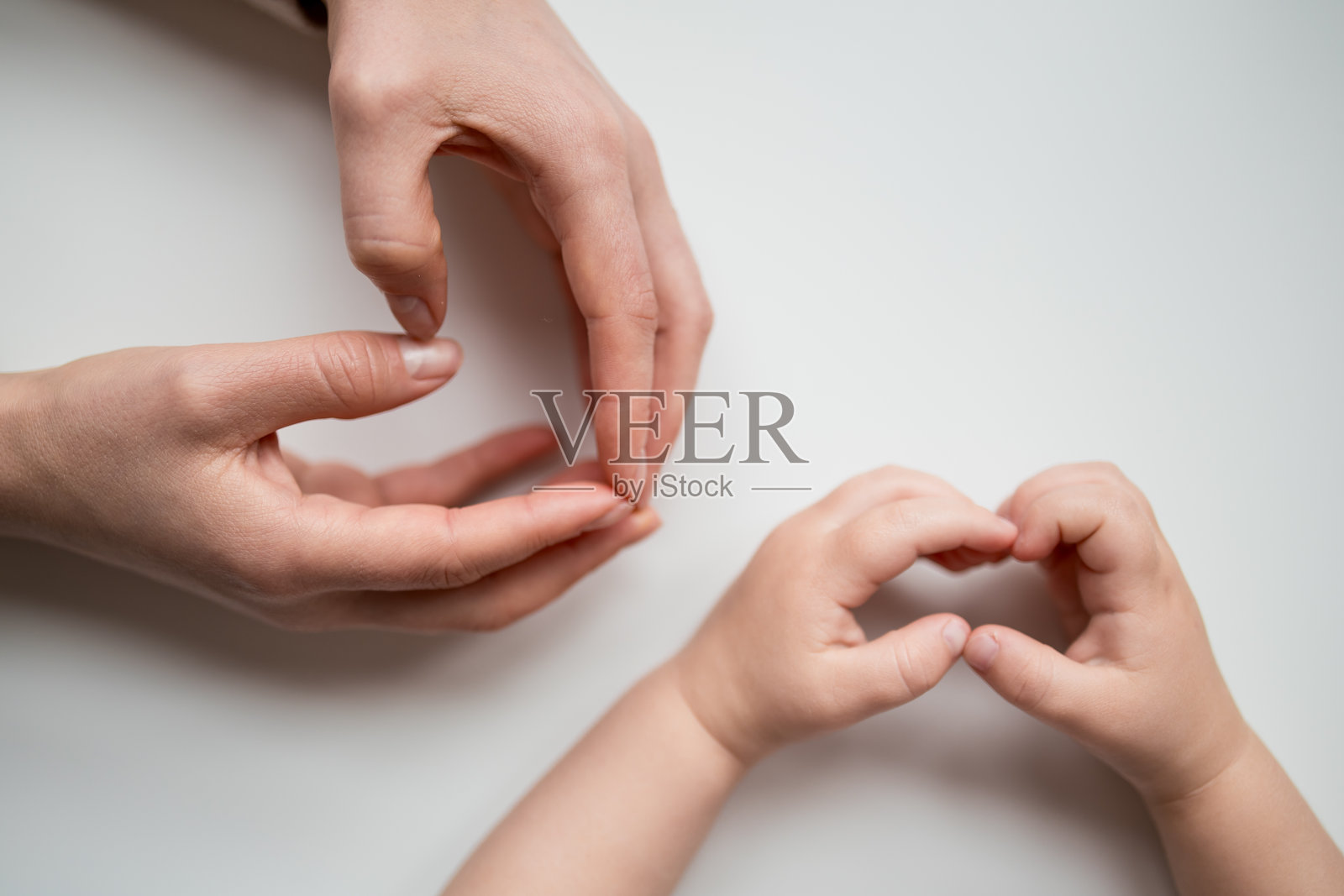 成人和儿童的手在白色背景上形成心形照片摄影图片