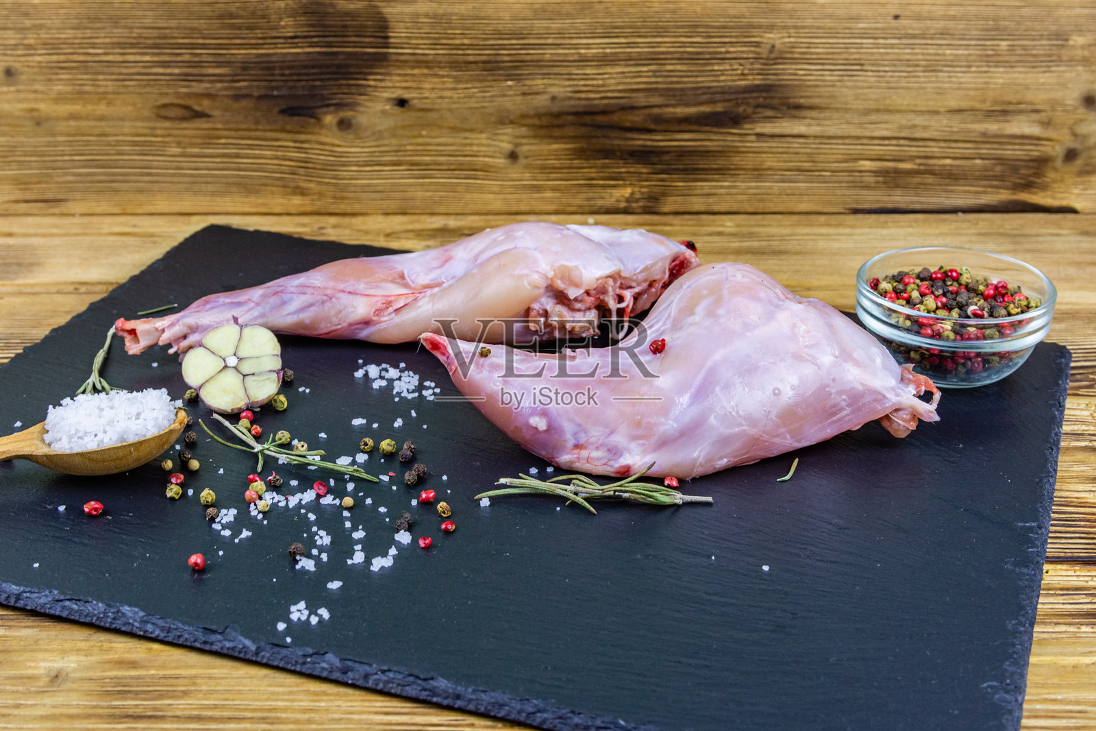 用黑板盛放的兔肉，配以胡椒、迷迭香、盐和大蒜照片摄影图片