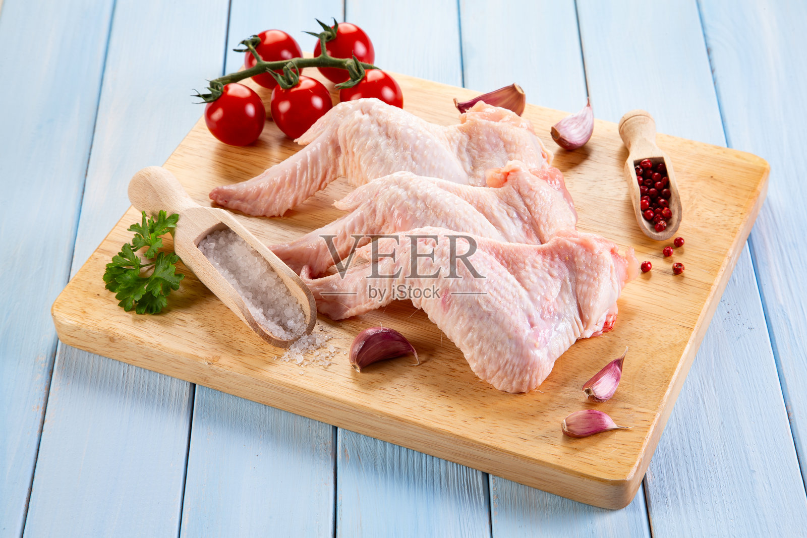 木桌上的切菜板上放着生鸡翅照片摄影图片