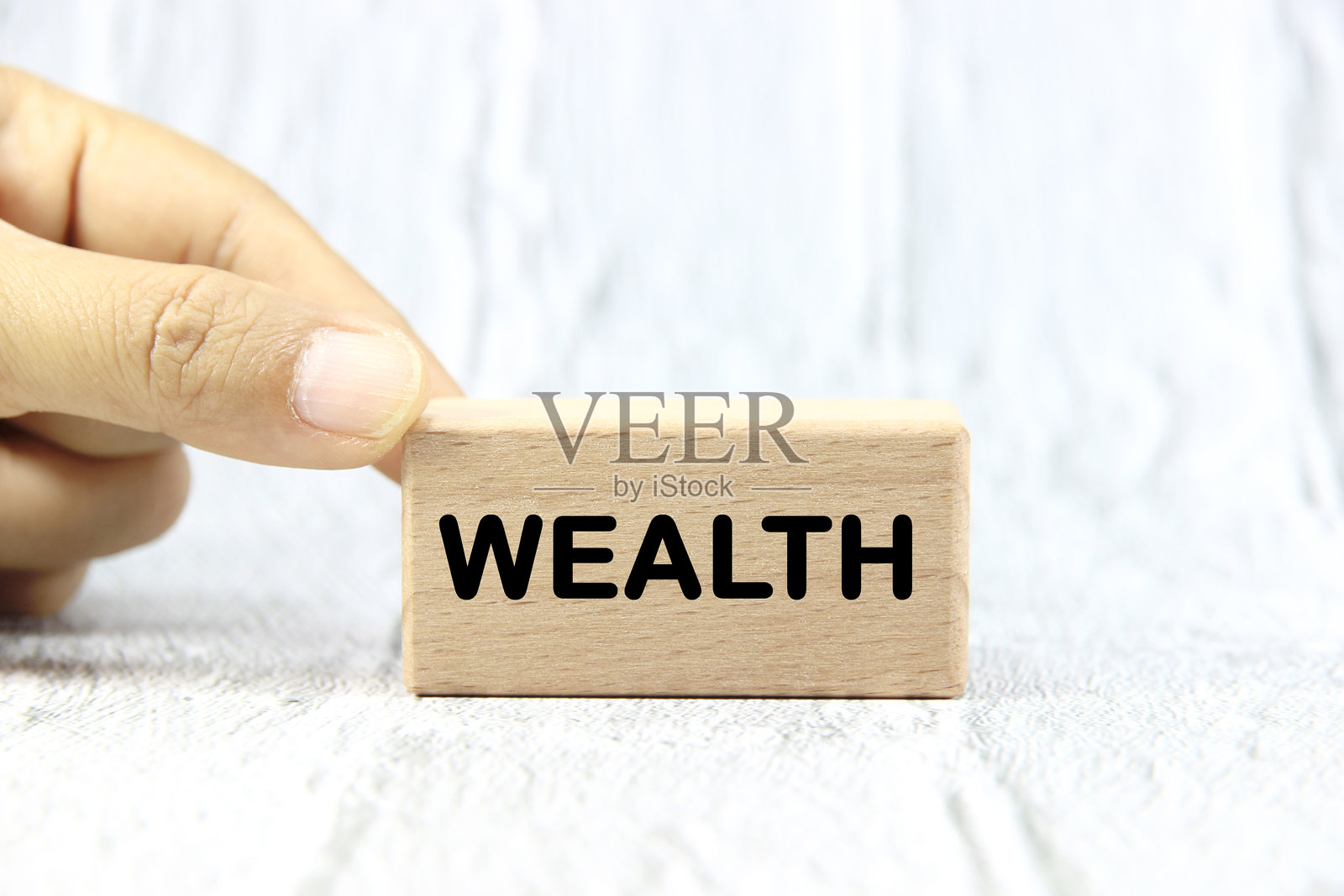 手握木块上的“财富”字样，象征金融与商业概念。照片摄影图片
