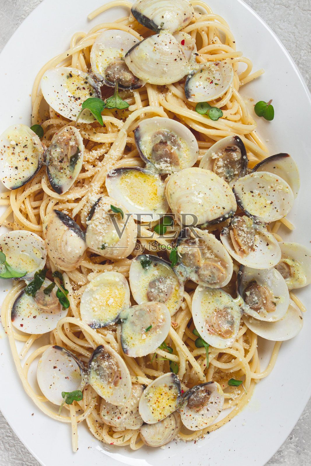 白盘上的意大利面配蛤蜊、奶油酱和卡邦尼，家常制作，俯视图，无人。照片摄影图片