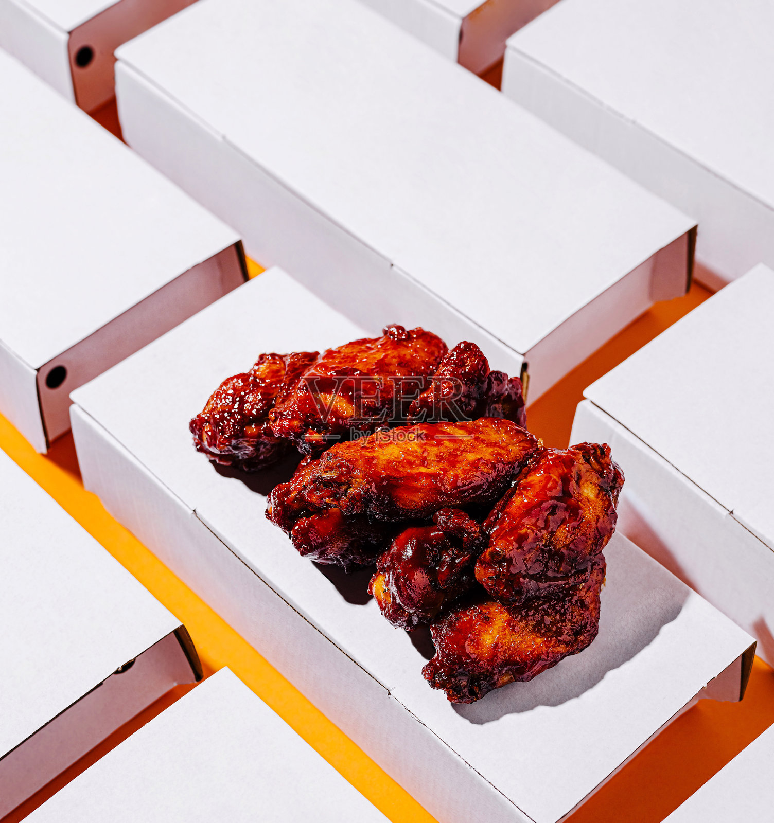 美味的鸡翅在橙色背景上，周围有多个空盒子。照片摄影图片