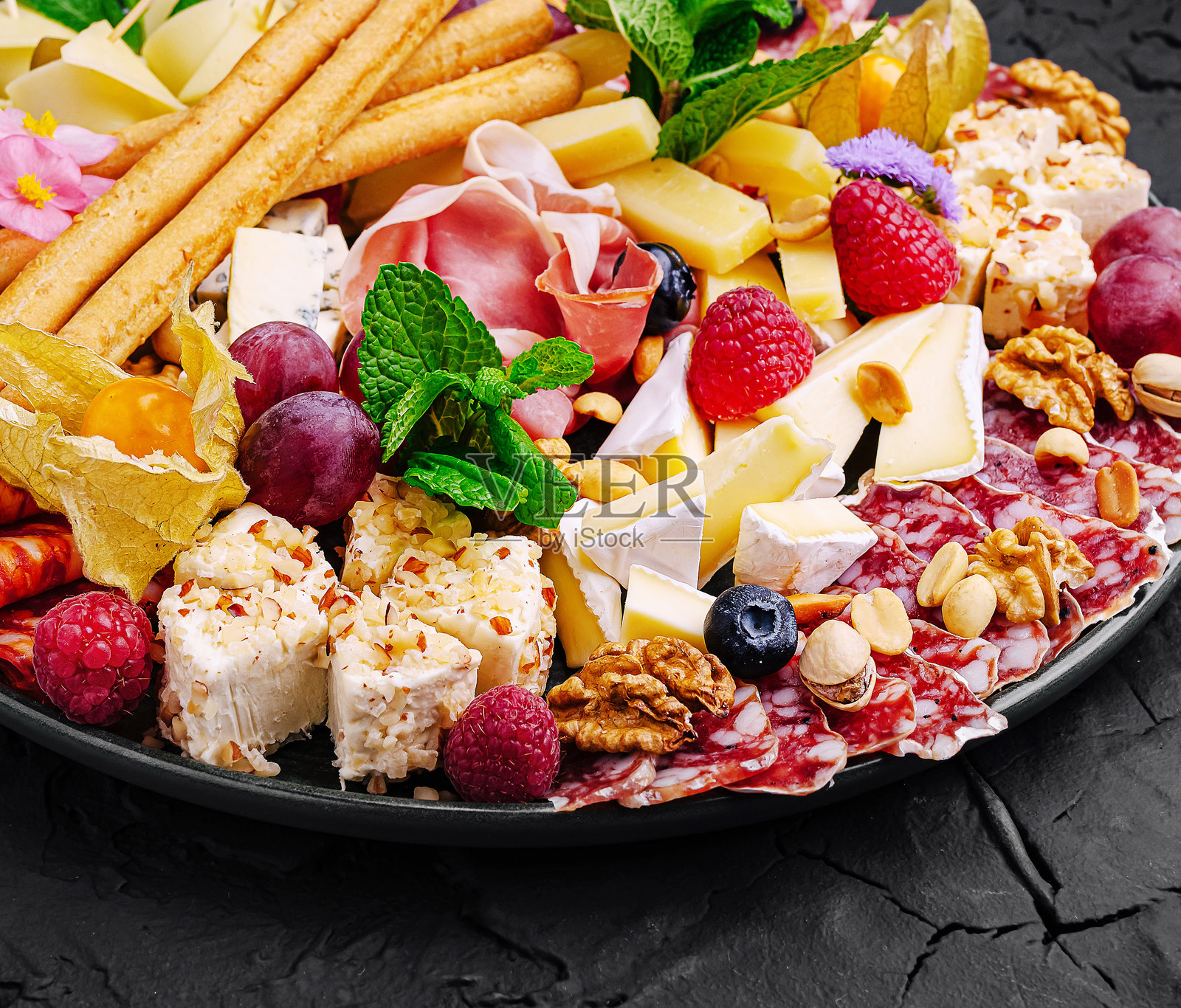 精美的肉类拼盘，展示了各种奶酪、肉类、水果和坚果，优雅地呈现于节日聚会中。照片摄影图片