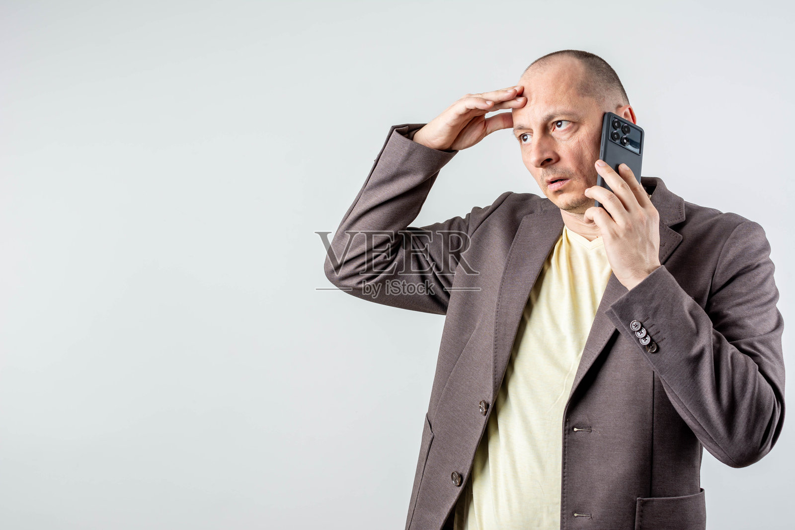 震惊的商人接听手机上的坏消息，背景为灰色照片摄影图片