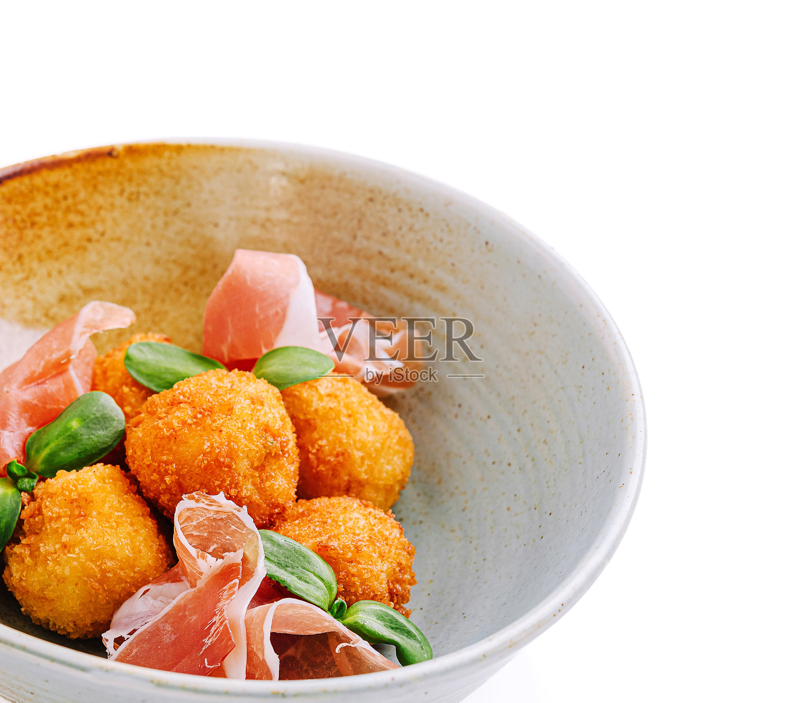 脆皮奶酪球，配以意大利熏火腿和新鲜香草，盛放在优雅的碗中照片摄影图片