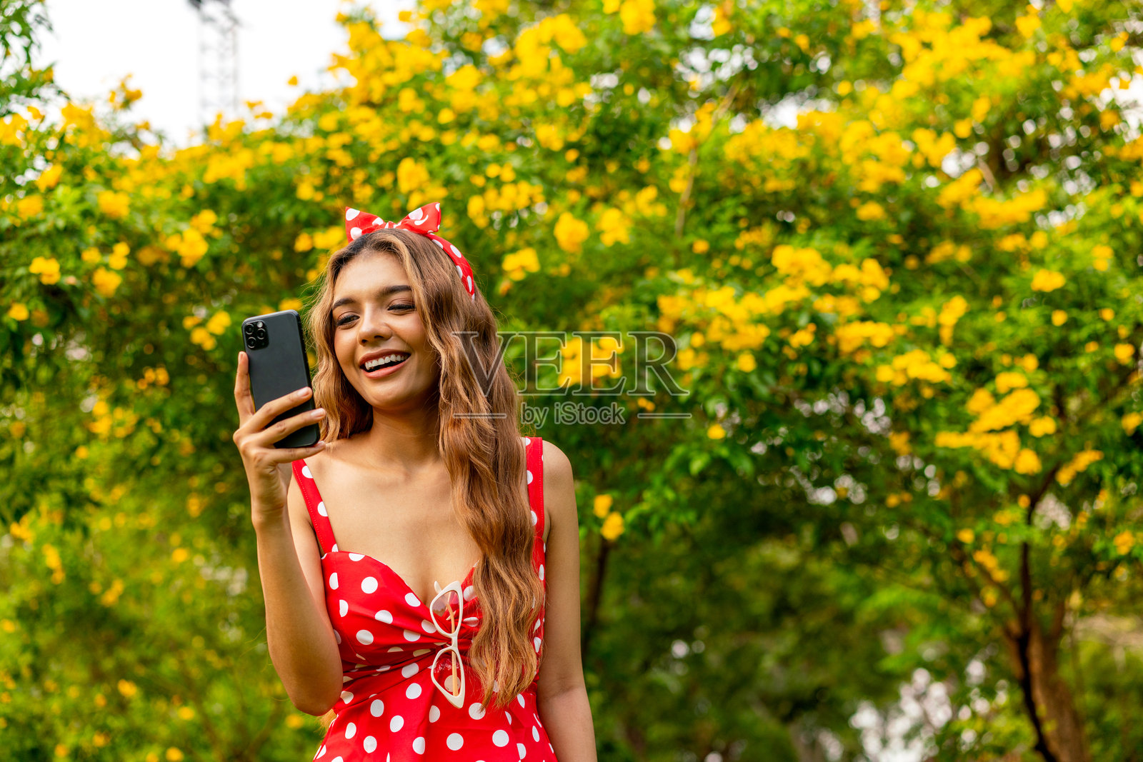 年轻女性穿着复古波点裙在公园户外使用手机照片摄影图片